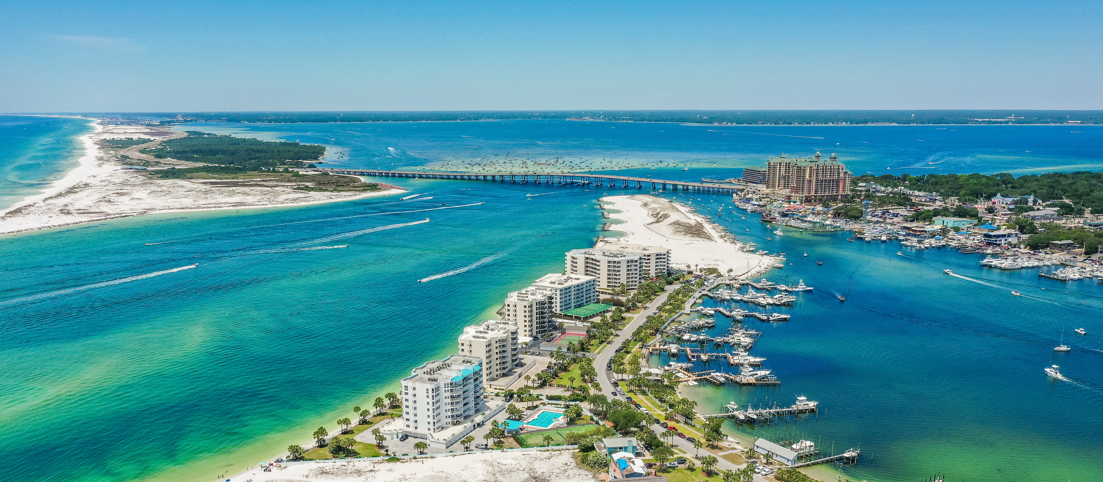 An aerial view of Destin Harbor highlighting the blues and greens of the Gulf